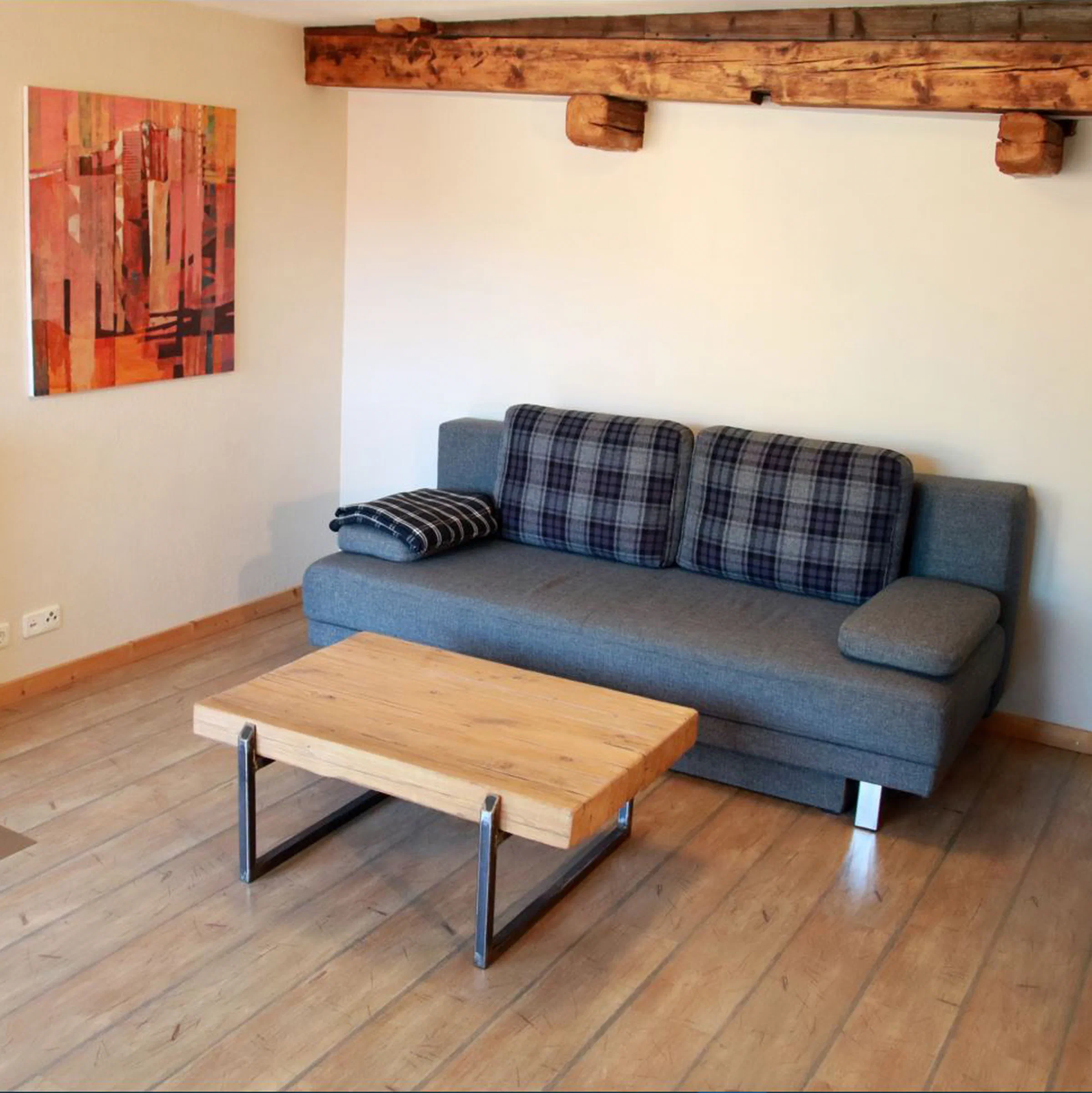 Wohnbereich mit grauem Sofa, Couchtisch und Kunstdruck an der Wand