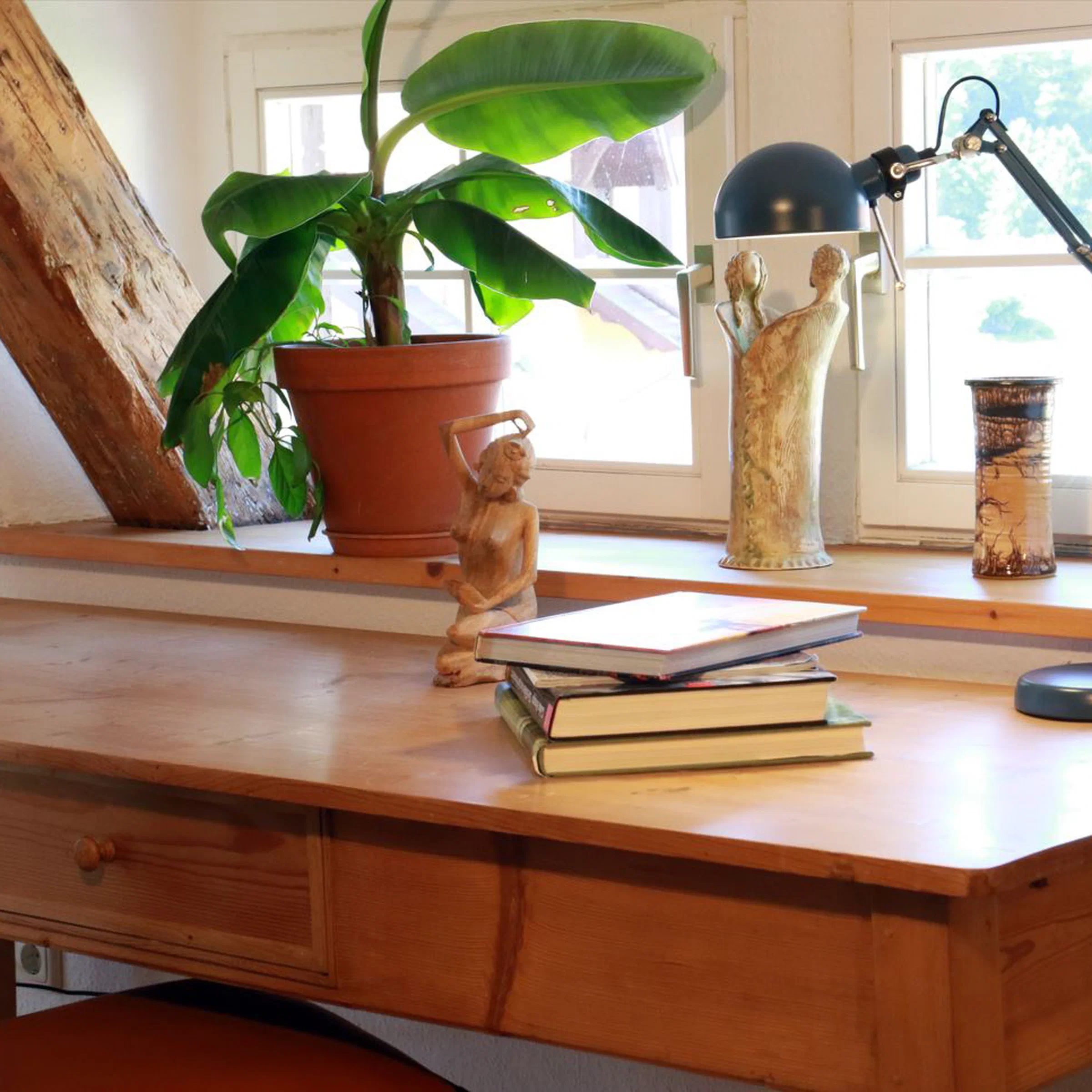 Schreibtisch mit Bananenpflanze und Blick aus dem Dachfenster