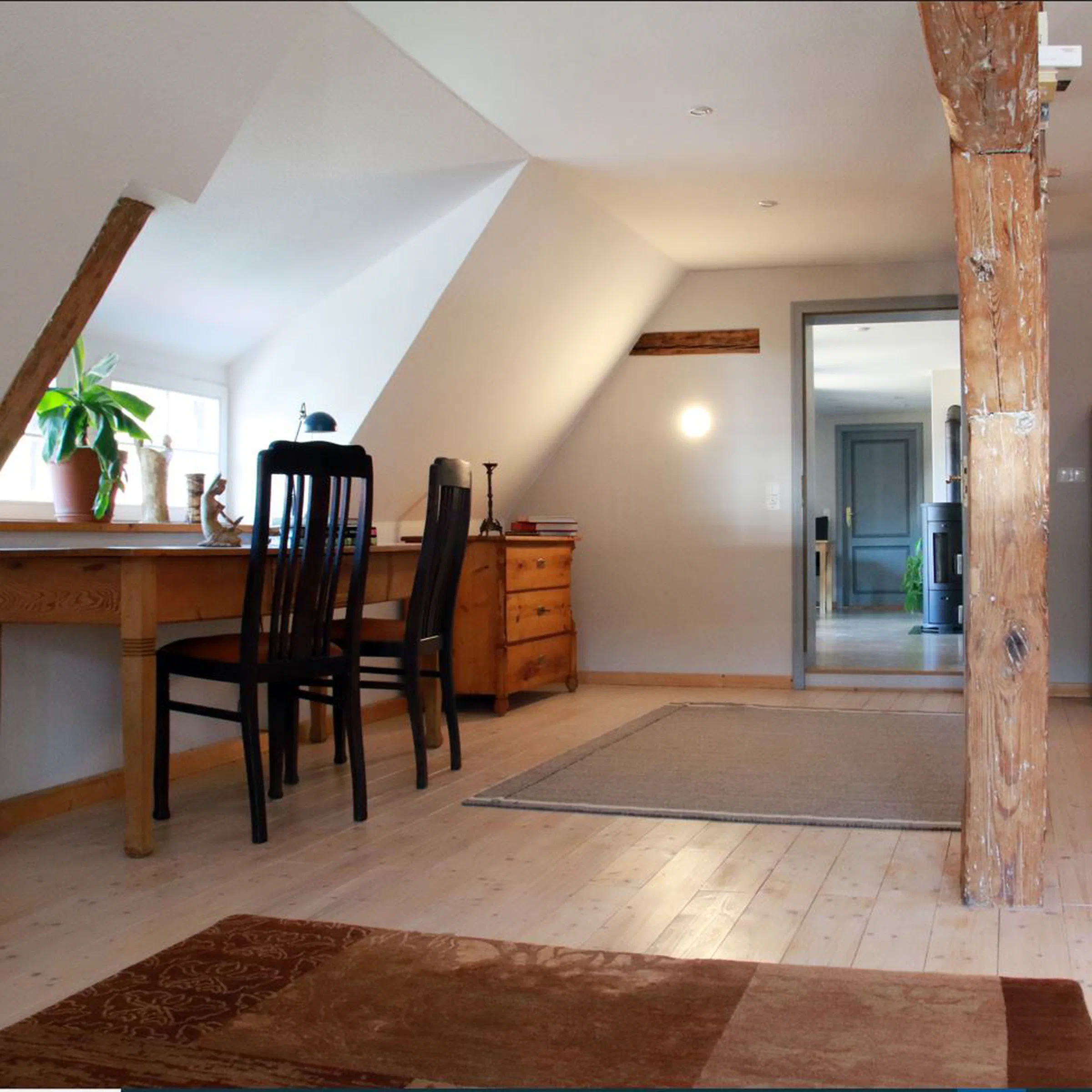 Wohnbereich mit Holzbalken und Blick zum Kaminofen im Nebenraum