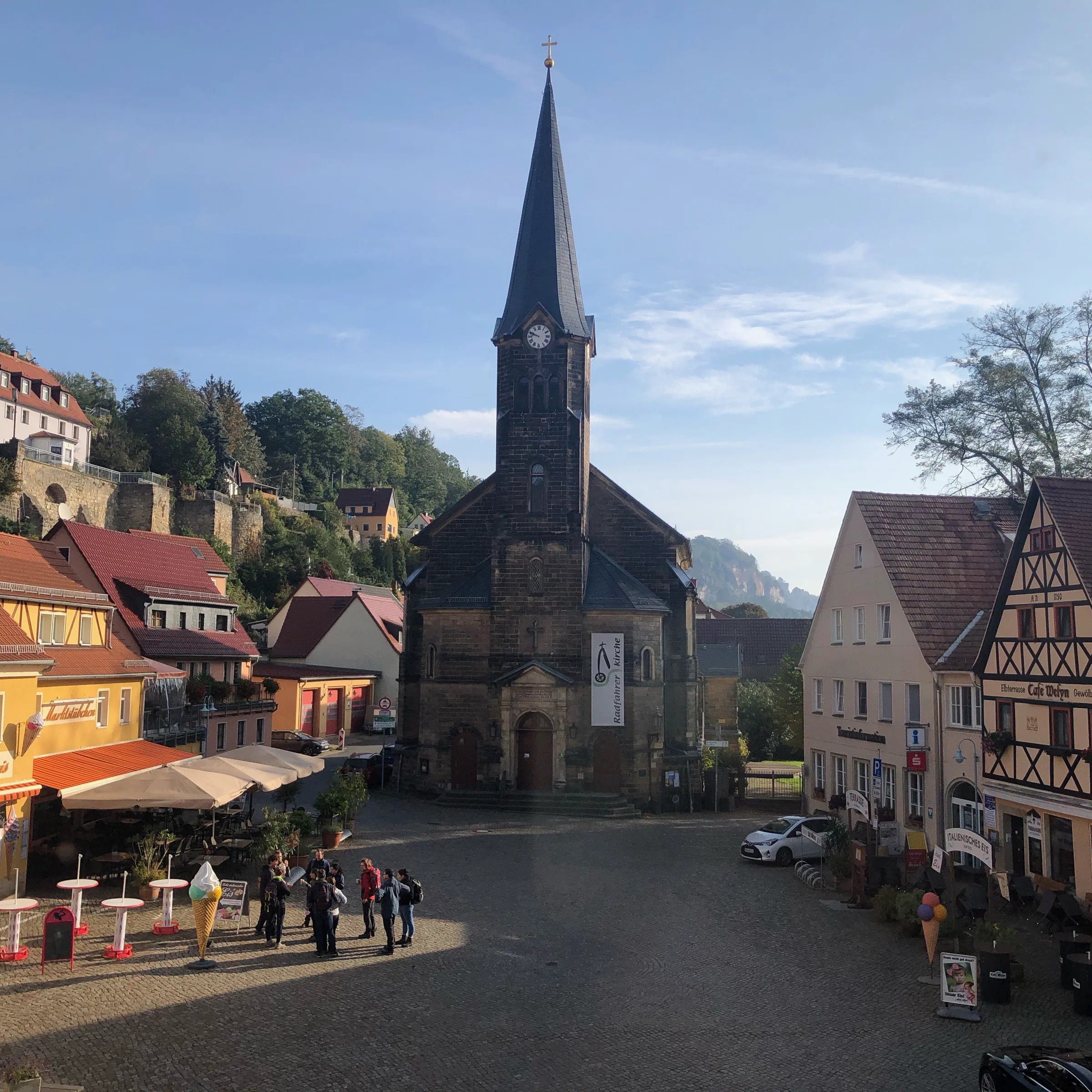 Marktplatz von Stadt Wehlen mit Kirche und Blick auf die Felsen der Sächsischen Schweiz