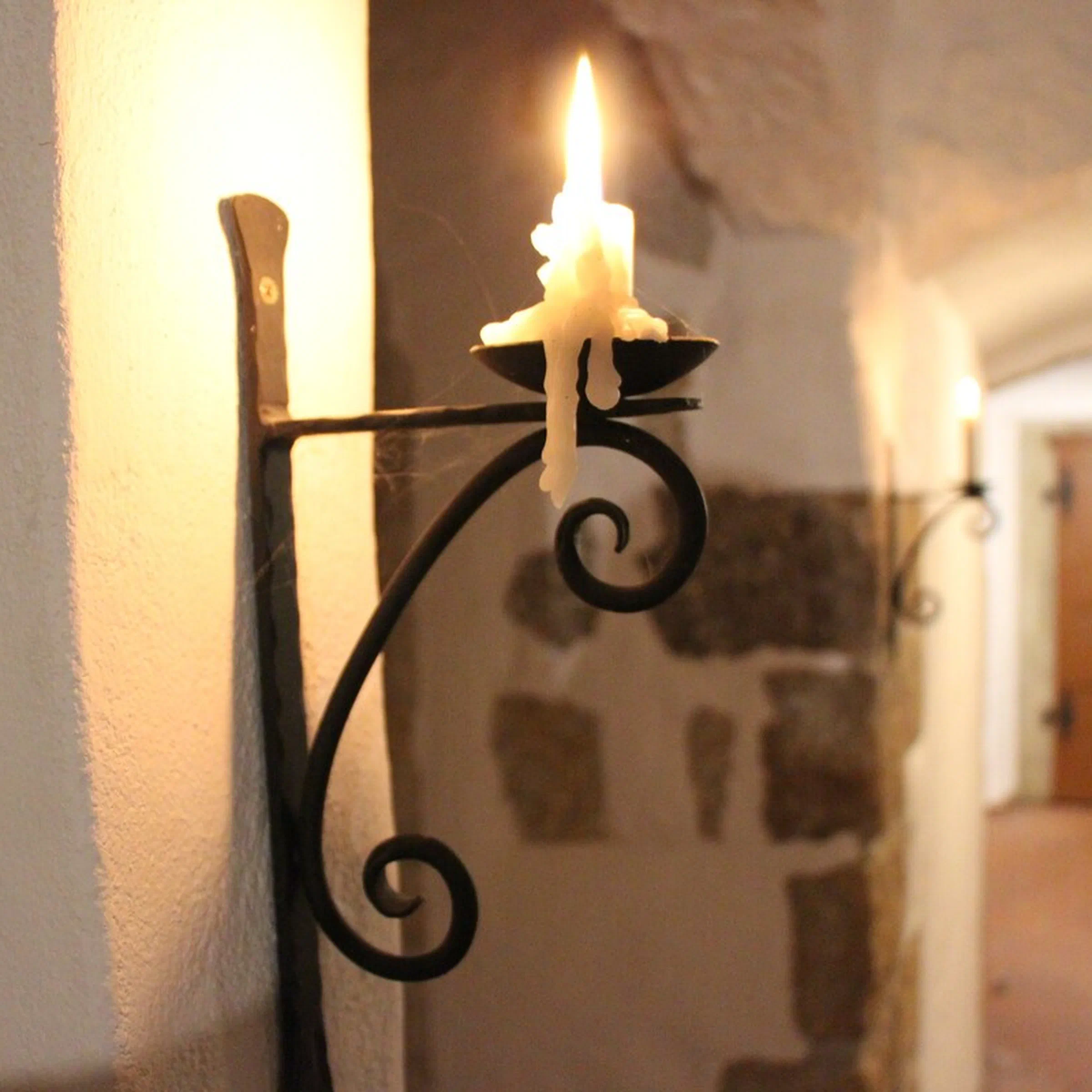 Kerze an schmiedeeisernem Wandhalter im Gewölbekeller